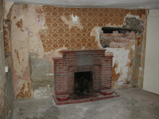 Buildings like Uvedales have been repaired and adapted over 100s of years. Here a modern fireplace in the east sitting room of the central ancient Uvedales stack is only the latest in a nest of fireplaces which, like Russian dolls, have filled up the space within the the original inglenook.It can be seen emerging from under the wallpaper.